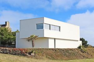 a white house on a hill with a palm tree at Vue Mer, Ports et Marina - Villa d'Architecte Haut de Gamme in Roscoff