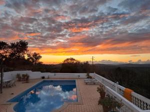 a swimming pool on a balcony with a sunset at Casa da azinheira in Loulé