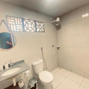 a bathroom with a toilet and a sink and a mirror at Porto Mirim House in Ceará-Mirim
