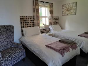 Inchmarlo Golf Resort, Banchory Villa 26 AS 00266F في بانشوري: سريرين في غرفة بها كرسي ونافذة