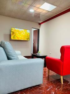 a living room with a couch and a red chair at La vida es bella! hermoso apartamento cerca al centro y aeropuerto in Pereira