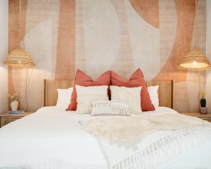 a bedroom with a white bed with red and white pillows at Ventana Cove Pickleball Retreat in Yucca Valley +71 photos