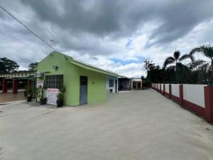 a green building with a fence and palm trees at Capital O 91117 Noor Room Stay in Taiping