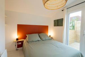 una camera da letto con letto con testiera arancione e finestra di La Résidence - Louez l'un de nos 4 appartements privés ! a Cholet