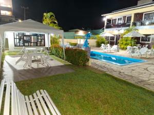 a yard with white chairs and a pool at night at Flat do Golfinho in Tamandaré +8 photos