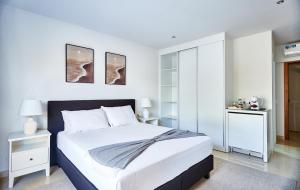a white bedroom with a large bed with white walls at Cam's Suites in Santa Maria +2 photos
