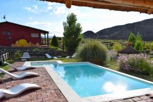 a pool in a yard with chairs and a house at Posada Malbec 3 Dormis in Uspallata