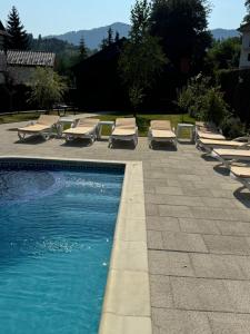 a swimming pool with chaise lounges and lounge chairs at Vila Luminita in Sângeorz-Băi