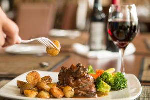 a plate of food with meat and vegetables and a glass of wine at Rincon del Valle Hotel & Suites in San José