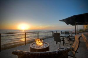 a fire pit on a patio overlooking the ocean at sunset at Oceanfront Getaway - Ocean Views - Fire Pit - BBQ - Beach Access in Carlsbad