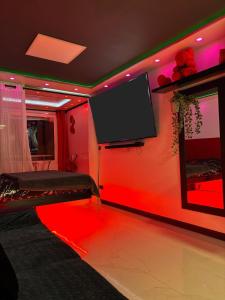 a room with a red wall with a flat screen tv at C12 Deluxe in Cap d'Agde