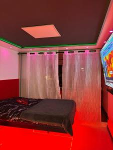 a bedroom with a bed and a tv and curtains at C12 Deluxe in Cap d'Agde