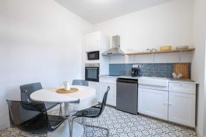 una cucina con mobili bianchi, tavolo e sedie di La Résidence - Louez l'un de nos 4 appartements privés ! a Cholet Altre 19 foto