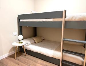 Un dormitorio con dos literas y una mesa. en Anais Apartments by gaiarooms, en Barcelona