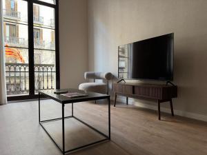 Una sala de estar con un televisor de pantalla plana y una mesa. en Anais Apartments by gaiarooms, en Barcelona