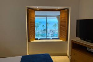 een slaapkamer met een raam met uitzicht op de oceaan bij Elegant with bars & beach access! in Puerto Vallarta
