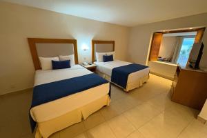 een hotelkamer met twee bedden en een televisie bij Suite with panoramic ocean views & balcony! in Puerto Vallarta +34 foto's