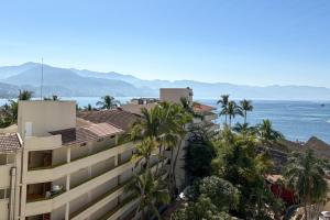 een uitzicht op een gebouw met palmbomen en de oceaan bij Suite with panoramic ocean views & balcony! in Puerto Vallarta