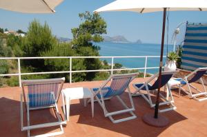a patio with chairs and an umbrella and the ocean at Casetta Nikà in Altavilla Milicia