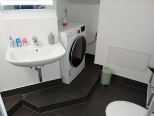 a bathroom with a sink and a washing machine at Eine wundervolle Wohnung! in Forstinning