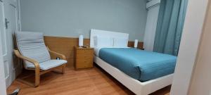 a bedroom with a bed and a chair at Residencial Sol da Nave in Porto