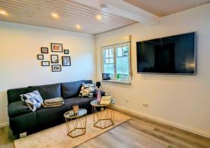 a living room with a black couch and a flat screen tv at Urlaubsresidenz Schlossblick in Colditz