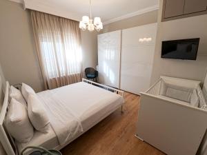 a bedroom with a white bed and a tv at Living Life Apartment Komotini in Komotini