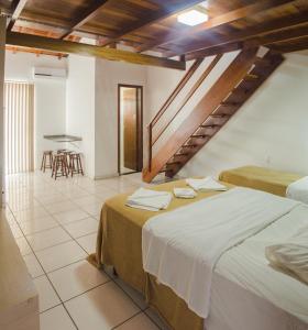 um quarto com duas camas e uma mesa ao fundo em Pousada Bronzatto em Garopaba