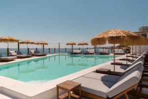 a swimming pool with chairs and umbrellas and the ocean at Luxury 3 Bedroom Apartment in Sliema - Walk to Beach & Dining in Sliema