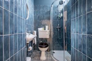 a blue tiled bathroom with a toilet and a sink at Greyfriars Bothy in St. Andrews +8 photos