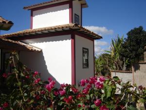 un pequeño edificio blanco con flores rosas en Pousada Villa Verde en Lavras Novas