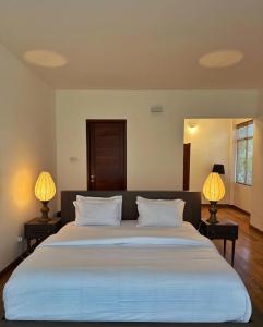 a bedroom with a large white bed with two lamps at Sanctuary Ceylon by Ceylon Spaces in Mount Lavinia
