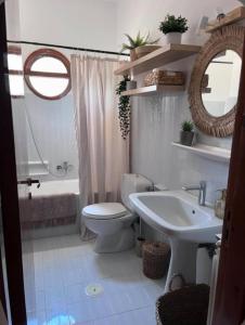 Un baño con inodoro, lavabo y espejo. en Castellano Apartments, en Afantou
