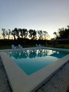 a swimming pool with chairs and a sunset in the background at Cabañas El Nono in Tandil