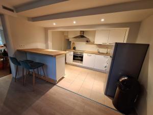 a kitchen with white cabinets and a counter and chairs at Cozy and perfectly located apartment in Rixensart