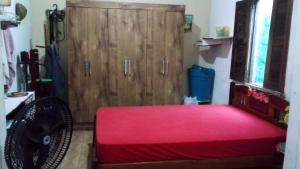 a bedroom with a red bed and a wooden door at Aconchegante e familiar in Marituba
