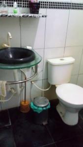 a bathroom with a white toilet and a sink at Aconchegante e familiar in Marituba