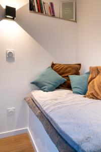 un letto con cuscini blu in una stanza di Neuf, confortable & atypique a Saint-Jean-de-Verges