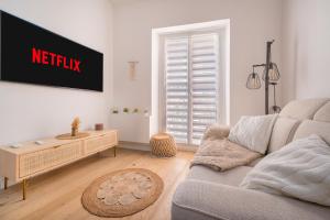 a living room with a couch and a tv on a wall at Le Duplex in Villefranche-sur-Mer