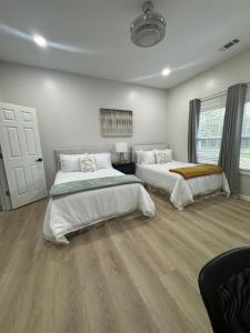 two beds in a room with white walls and wood floors at Richland Villa in Vidalia