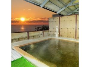 an indoor pool with a sunset in the background at Hotel Tetora Resort Tsuruoka - Vacation STAY 39431v in Tsuruoka