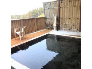 ein Swimmingpool in einem Hinterhof mit einem Tisch und einem Stuhl in der Unterkunft Hotel Tetora Resort Tsuruoka - Vacation STAY 39411v in Tsuruoka