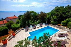 - une piscine avec des chaises et une vue sur l'eau dans l'établissement Apartments Villa Iva, à Ravni