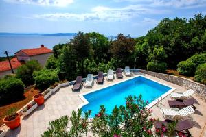 a swimming pool with chairs and a view of the water at Apartments Villa Iva in Ravni