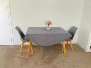 una mesa con dos sillas y un jarrón con flores. en Living Oasis, en Auckland