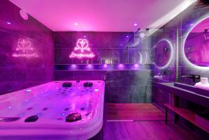 uma casa de banho com uma banheira com luzes roxas em L'Inséparable - Jacuzzi - Terrasse - Parking - Vélos em Fondettes mais 39 fotografias