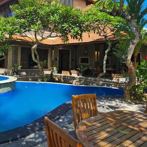 a pool with a wooden table and chairs next to a house at Villa Djojonagoro in Ketewel +22 photos