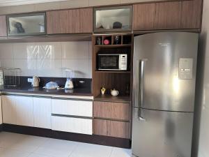 a kitchen with a stainless steel refrigerator and cabinets at Sobrado top com piscina, espaço gourmet, próximo à praia com Ar Condicionado in Itanhaém