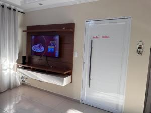 a living room with a tv and a sliding door at Sobrado top com piscina, espaço gourmet, próximo à praia com Ar Condicionado in Itanhaém