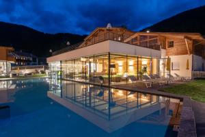 ein Haus mit Swimmingpool bei Nacht in der Unterkunft Alpine Nature Hotel Stoll in Gsieser Tal